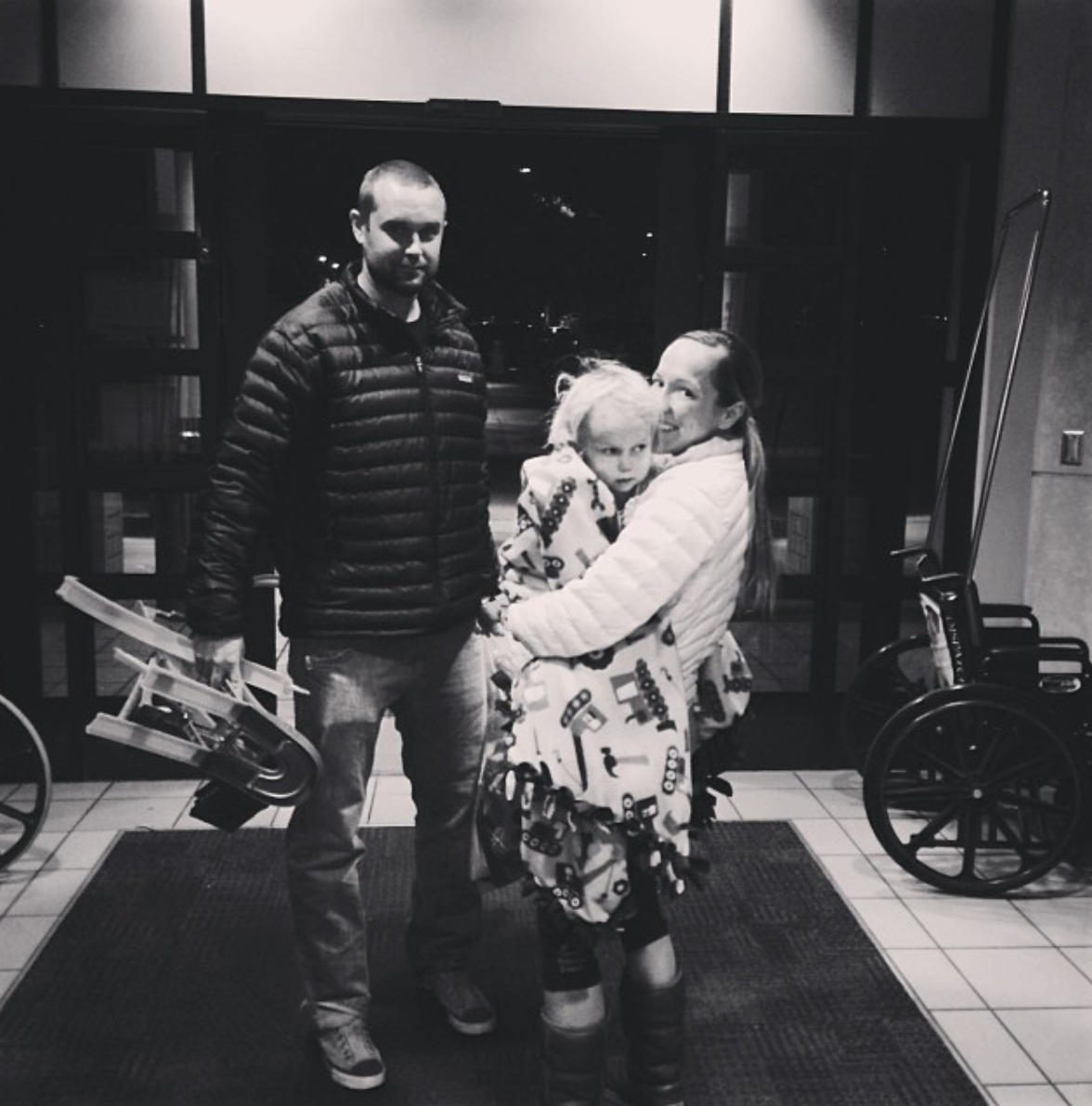 two parents holding their son in the entry way of a hospital 