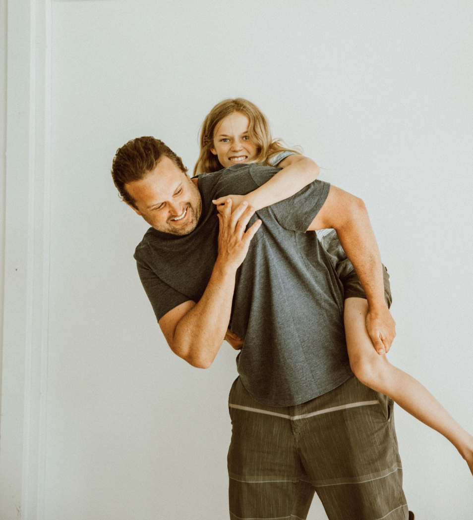 father laughing while holding his son in piggy back position