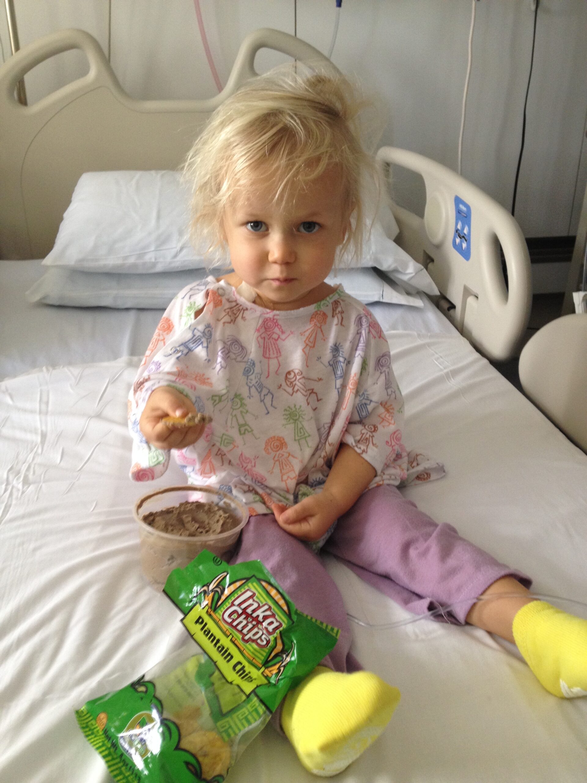 little boy with cancer in hospital eating gluten free lunch of plantain chips and pate