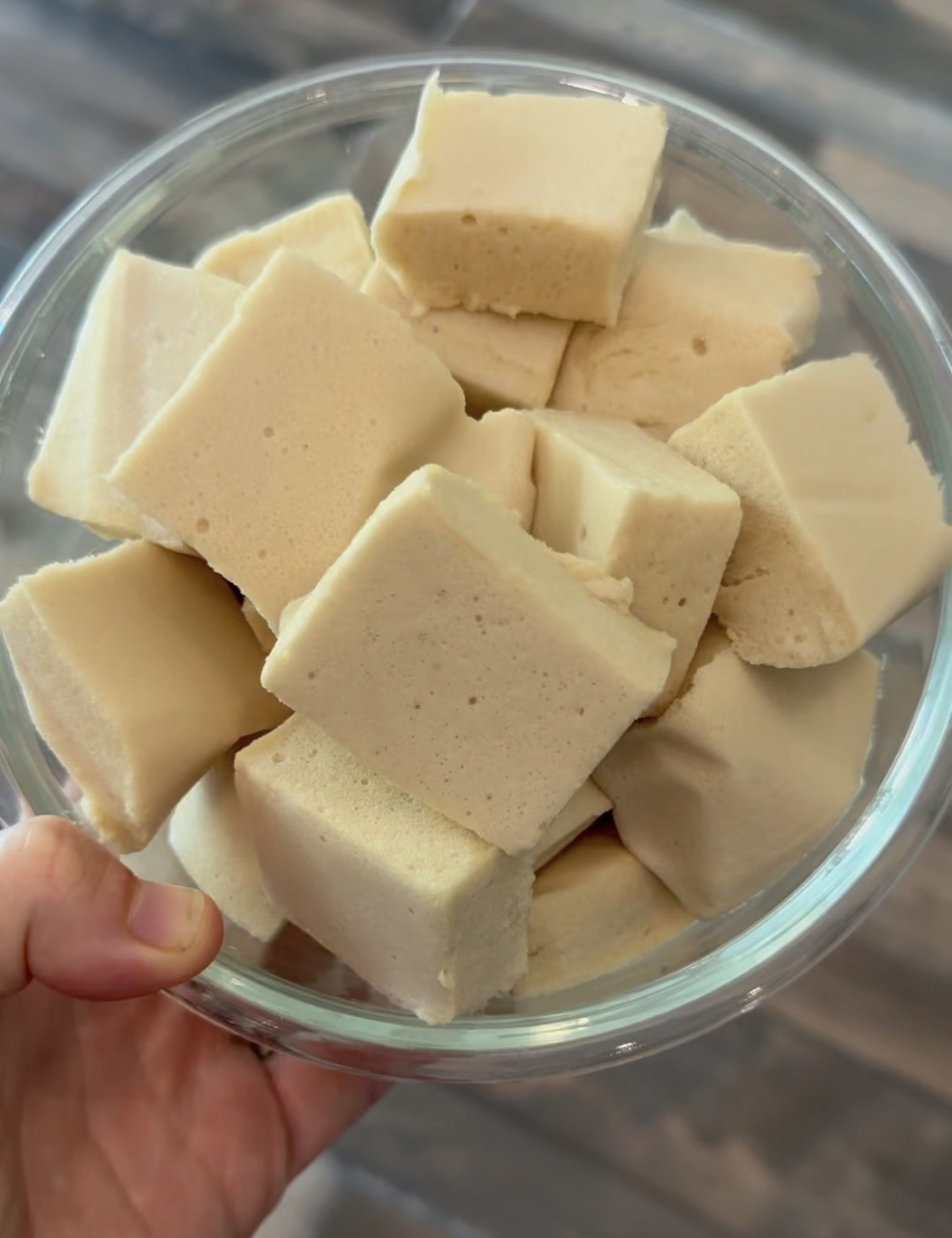a hand holding a bowl of homemade marshmallows